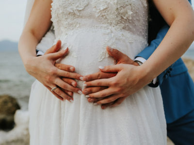 Χέρια γαμπρού και νύφης πάνω στην κοιλιά της εγγύου νύφης