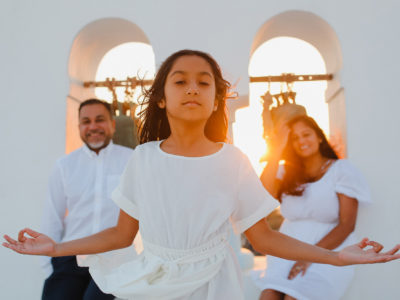 family portrait, daughter in a meditation position while parents are visible and a bit out of focus in the background