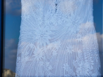 wedding dress behind the window with clouds reflection and blue sky on it