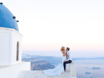 Elopement in Santorini, bride and groom on a churches blue dome rooftop with view at the caldera