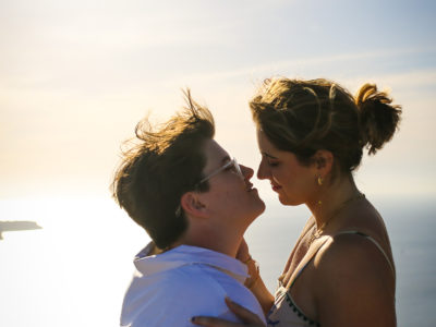 location portraiture of two lesbian women by Santorini caldera, same sex proposal